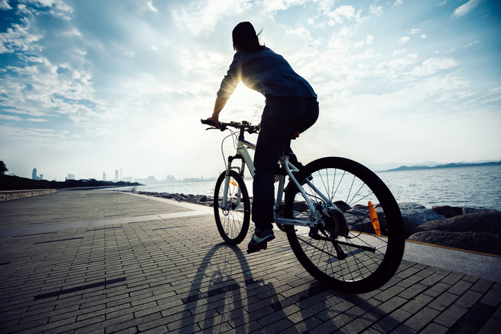 太陽の光を浴びながら自転車をこぐ女性
