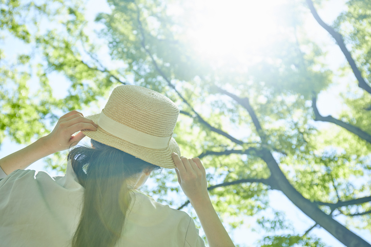 帽子を持って日差しを浴びる女性