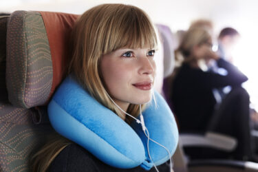飛行機のなかでネックピローを付ける女性