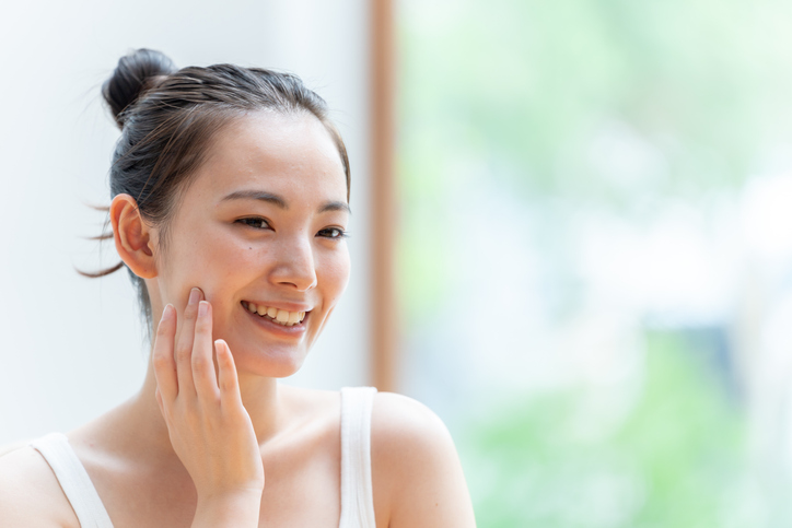 肌をさわる笑顔の女性