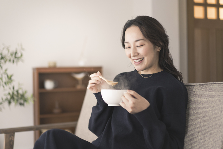 笑顔でスープを飲む女性