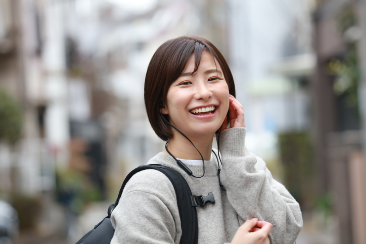 ワイヤレスイヤホンを装着して笑顔の女性