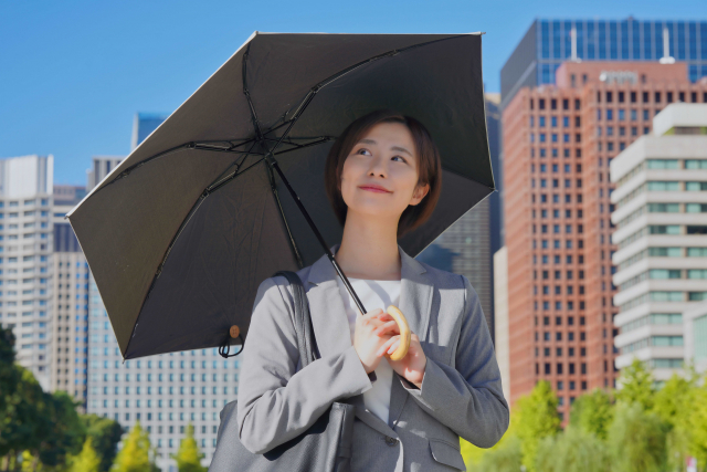 完全遮光の日傘をさすビジネスウーマン