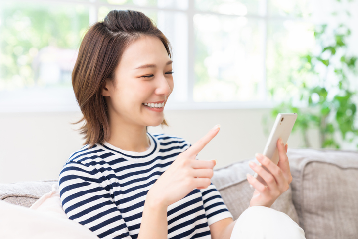 携帯電話をみて笑顔の女性