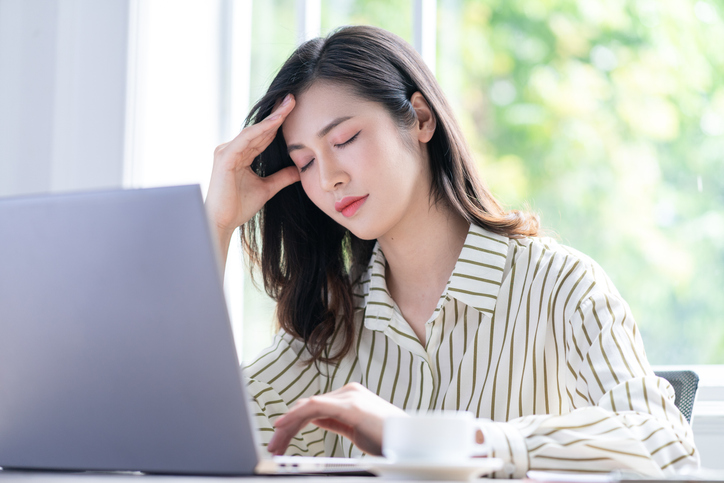 頭痛で頭をおさえる女性