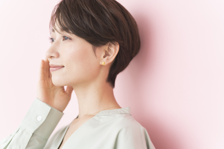 肌をさわる笑顔の女性